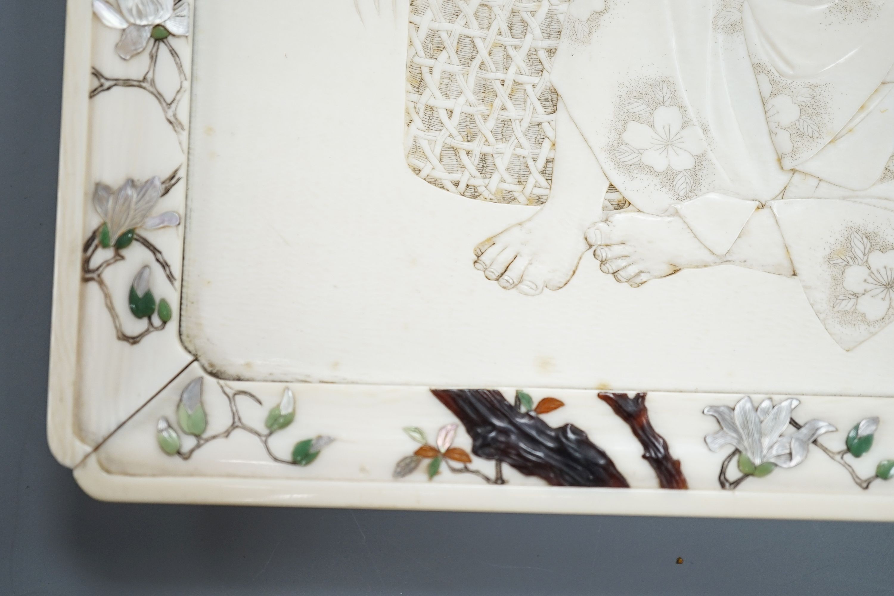 A Japanese ivory tray/plaque, Meiji period, with sunk-in carving of boy with dove, the surround decorated with Shibayama inlaid flowers etc. 15 x 20cm